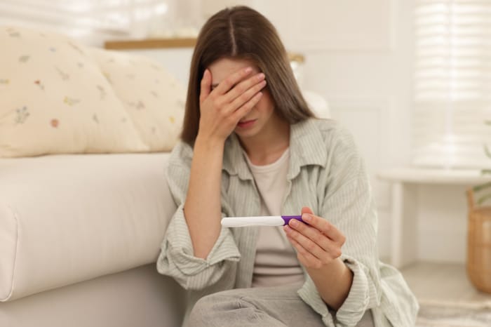 Sad woman looking at pregnancy test (Illustration ONLY)