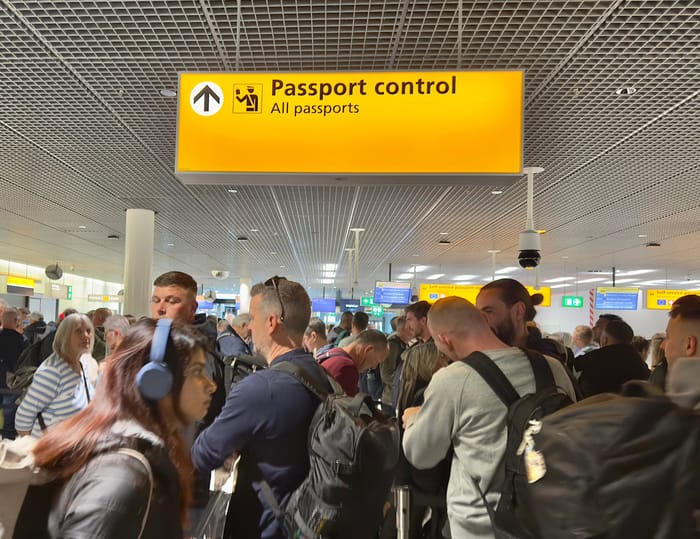 Passengers waiting in line to clear passport control at Amsterdam Schiphol Airport.