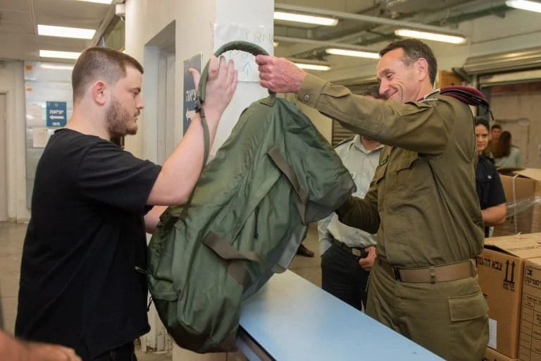 Halevi hands out a logistics bag to a recruit