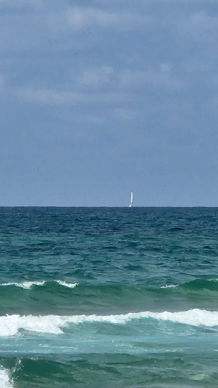 Calm sea with a white sail in sight