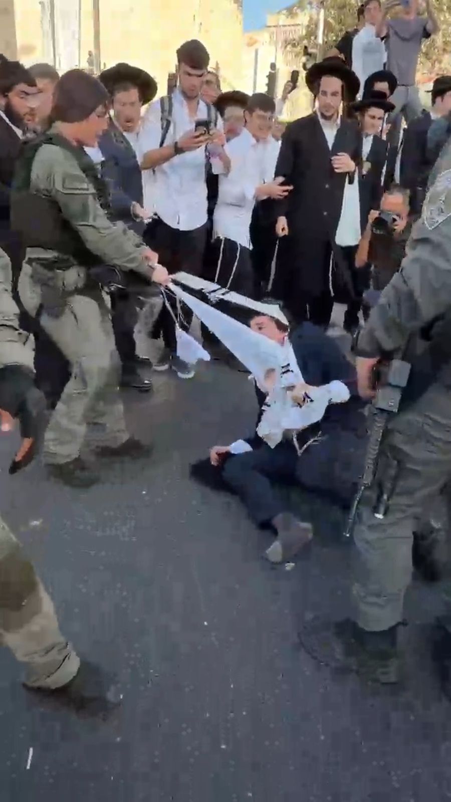 Officer tearing tzitzis from protester
