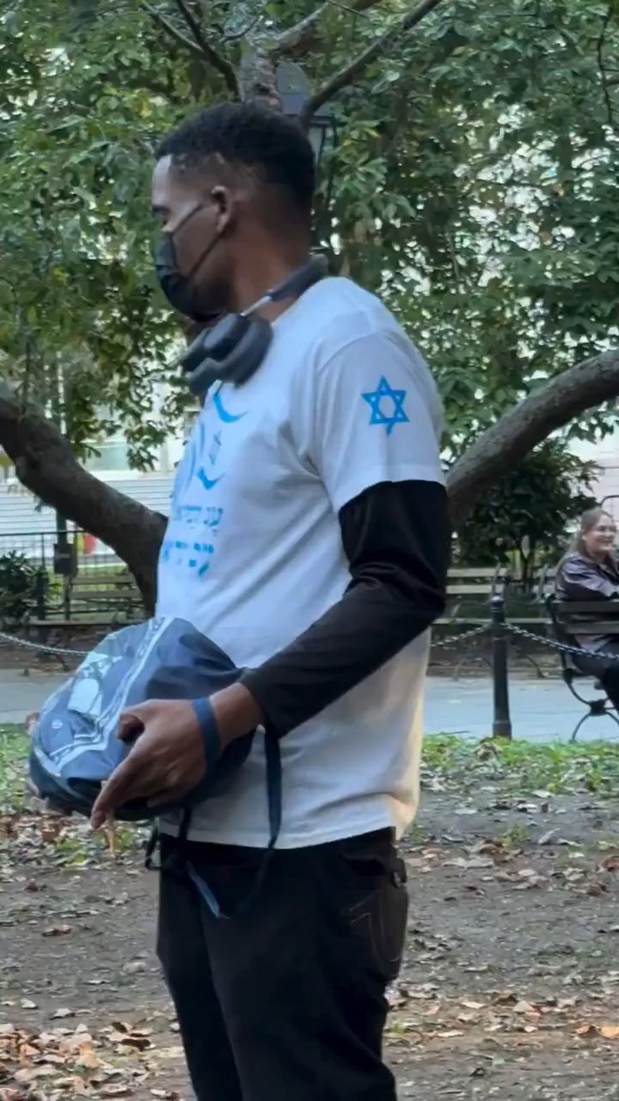 A young Black man wearing an Israeli flag shirt faces Satmar bochurim holding Palestinian flags