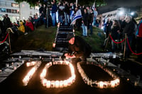 A man lights candles to mark 100 days since the start of the war during a protest against Israeli Prime Minister Benjamin Netanyahu and the current Israeli government, in Tel Aviv, January 13, 2024.