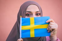 Muslim woman in a scarf holds flag of Sweden 