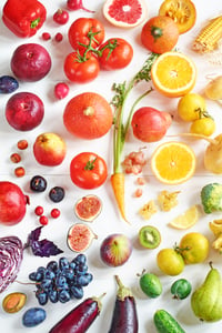 Rainbow colored fruits and vegetables on a white table