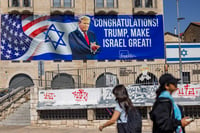 Pepole walk next to a sign congratulating U.S. President Donald Trump for his victory in the US presidential election in central Jerusalem