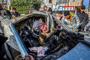 Palestinians at the site of a destroyed car after it was hit from an Israeli air strike in Rafah, in the southern Gaza Strip, on January 21, 2024.
