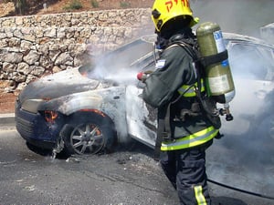An Israeli fire fighter extinguishes a fire following a car accident.