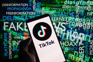  TikTok icon logo displayed on a smartphone with disinformation on screen seen in the background