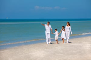 Happy family walking on the sand on a sunny beach