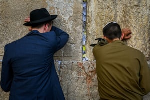 An Israeli soldier prays next to an ultra orthodox Jewish man at the Western Wall in Jerusalem's Old City