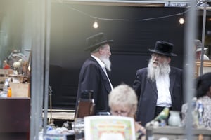 Two elderly Orthodox Jewish men with beards wearing black coats and hats chatting in Spitalfilds market