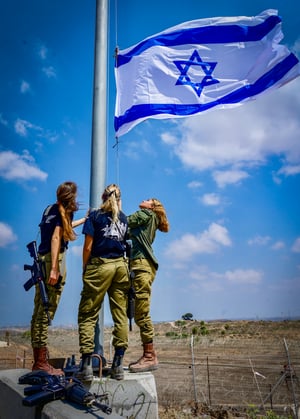 Israeli soldier hang an Israeli flag in Kibbutz Nir Am, near the Israeli border with the Gaza Strip, August 12, 2024. 