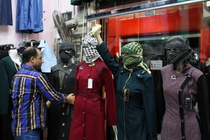 A Palestinian man display mannequins wearing keffiyeh at his shop in the southern Gaza Strip