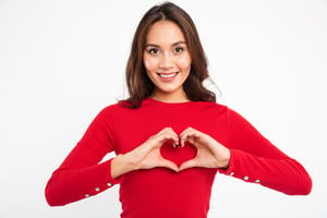 Portrait of a smiling young woman showing heart gesture