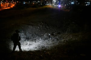 Israeli security forces at the site where a missile fired from Lebanon hit a road near in the northern Israeli city of Haifa