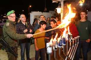 IDF Lt.-Col Asman (L), Oded Ravivi, head council of Efrat and Students from Yeshivat Orot in Efrat light the Hanukkah candles at the Gush Etzion Junction