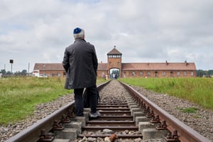 Jewish man stands in front of Auschwitz 