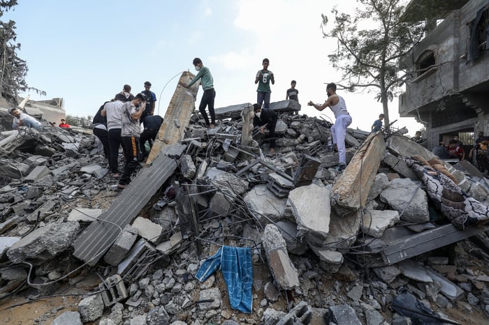 Palestinians search a house after an Israeli air strike, in the city of Rafah, southern of the Gaza Strip