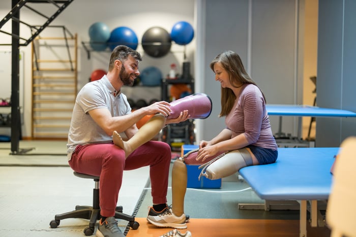 Physiotherapist helping young woman with prosthetic legs 