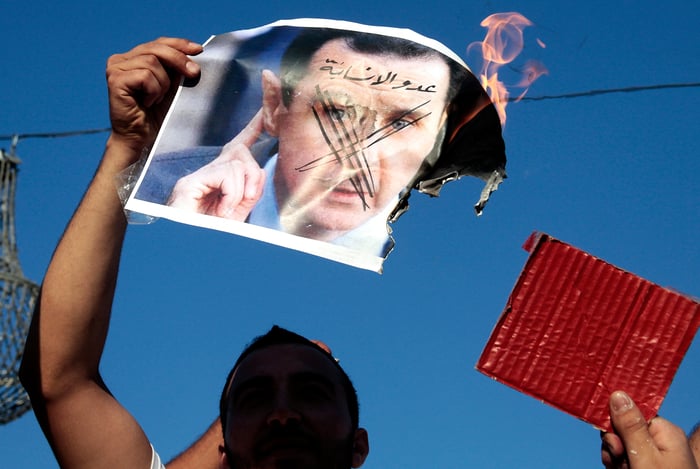 Protestors burning Assad's image.