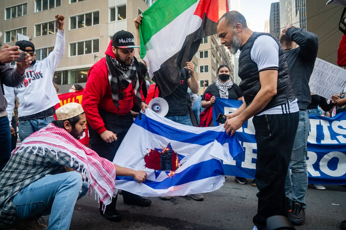 Protestors burning an Israeli flag.