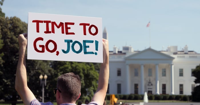 A man holds a "Time to Go, Joe" in front of the White House