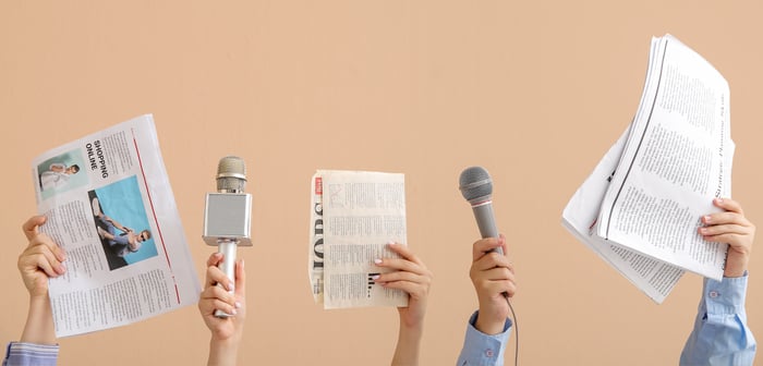 Female hands with microphones and newspapers on beige background 