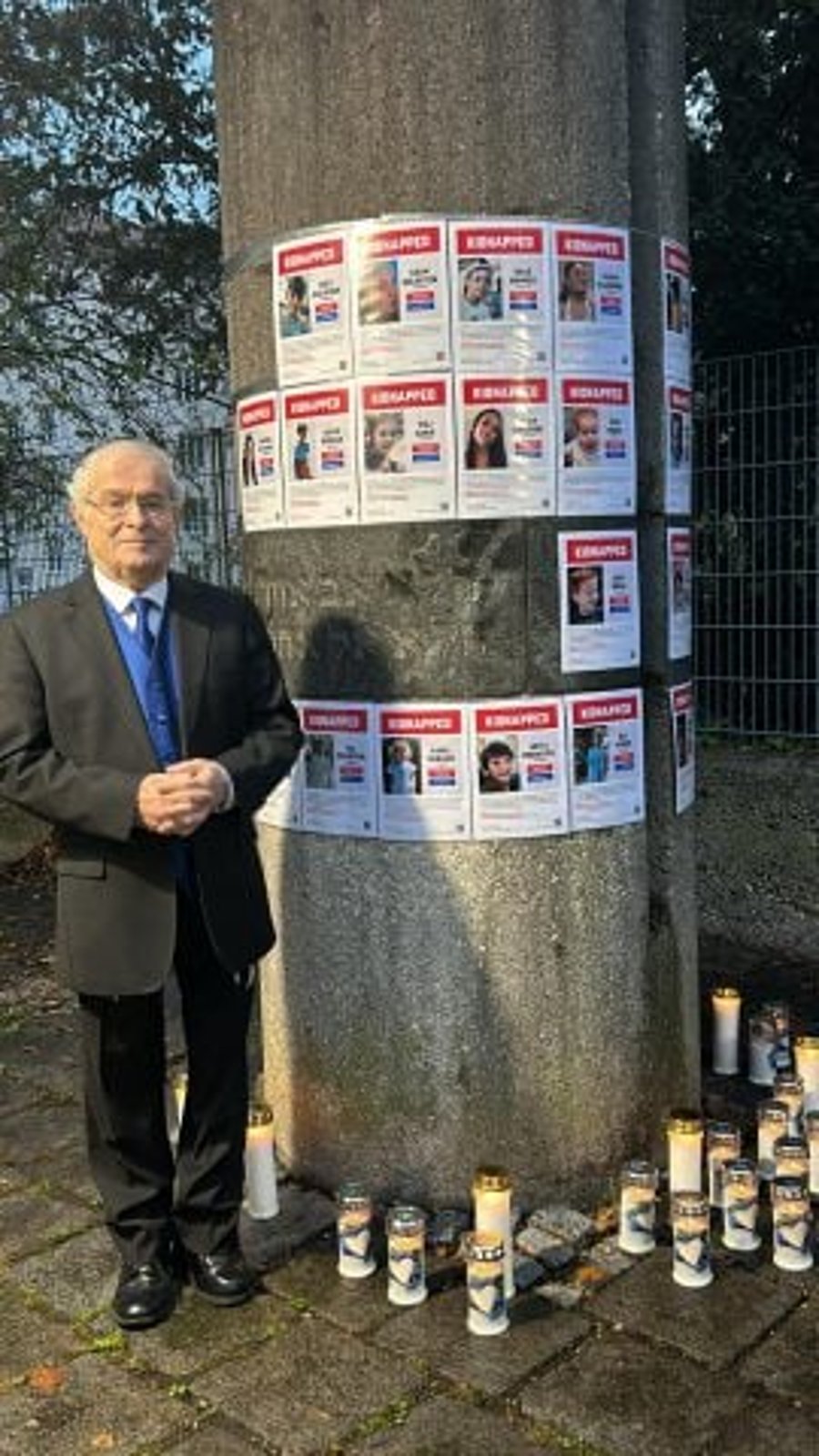 Maestro Eli Yaffe next to the pictures of the abductees