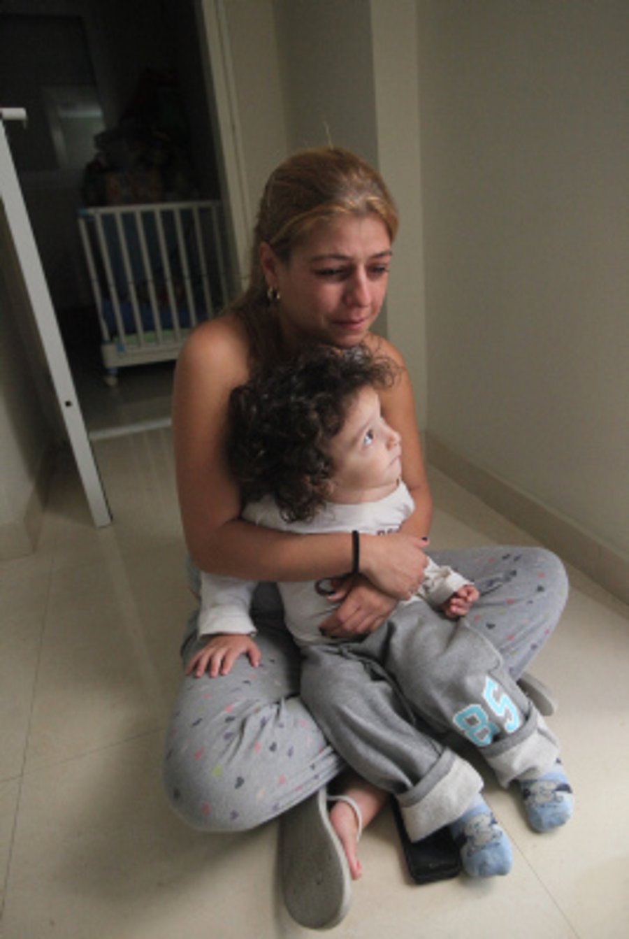 A mother hugs her child as they sit in the safe zone while a siren sounds in the town of Ashkelon