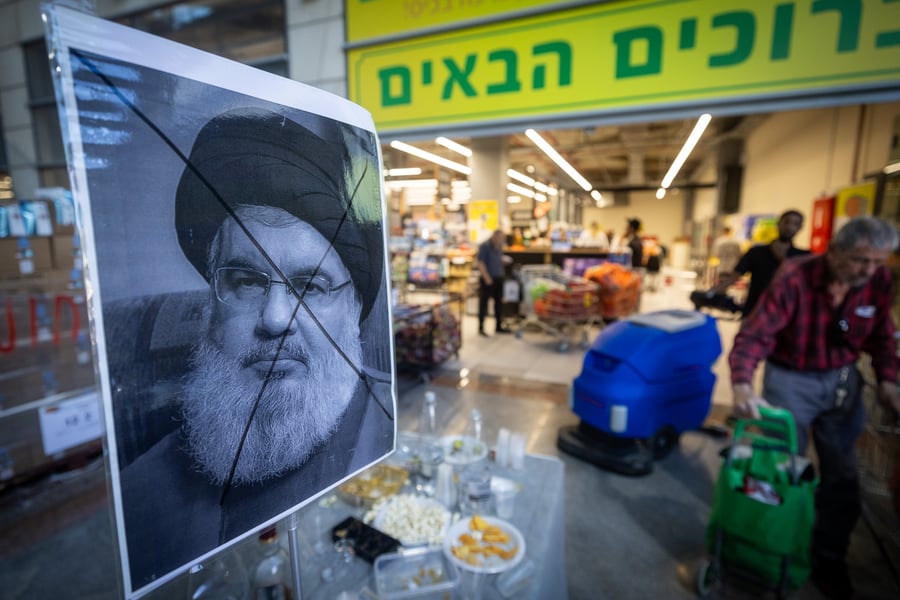 A portrait of Hezbollah leader Hassan Nasrallah with an X sign on his face is placed on a table with drinks and food to celebrate his assassination by Israel, outside a supermarket in Jerusalem, September 29, 2024. 