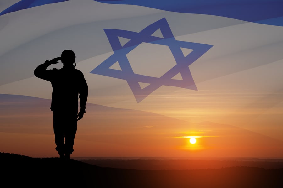 Silhouette of soldier saluting against the sunrise in the desert and Israel flag