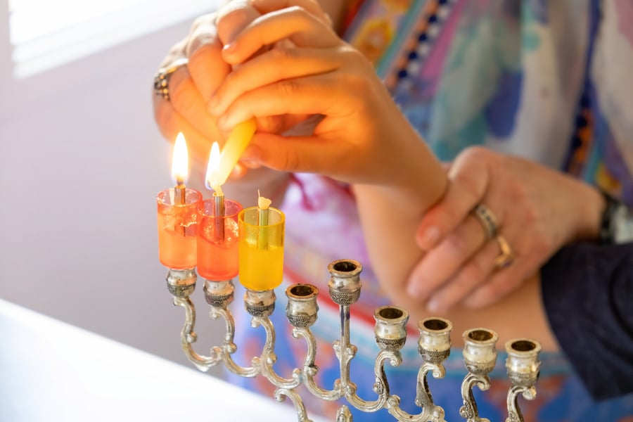 Woman helping a child to light Hanukkah candles