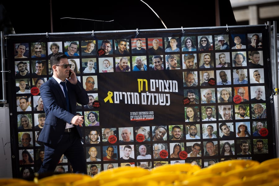 Man passing a poster for the release of the hostages.