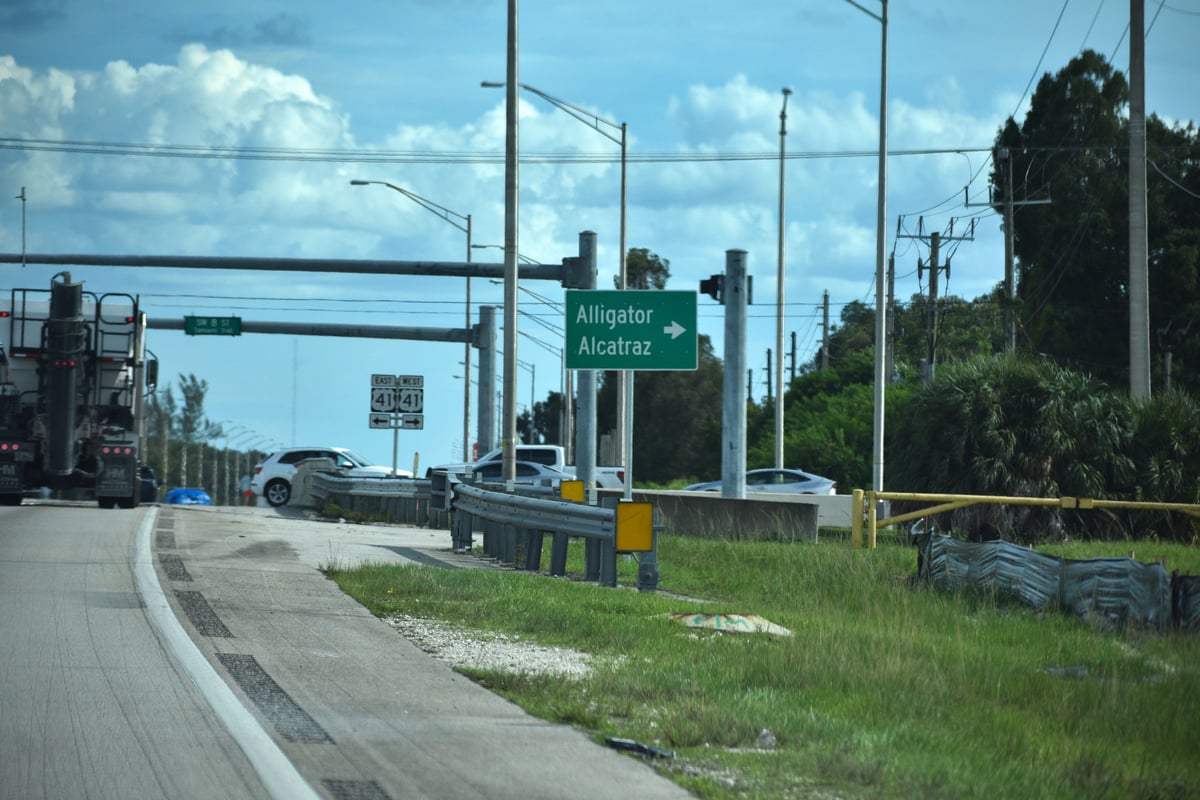 A road sign directing drivers to the immigrant detention center known as "Alligator Alcatraz."