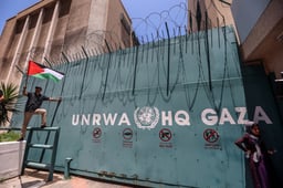 Palestinian refugees gather with national flags outside UNRWA in Gaza