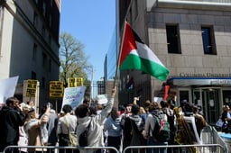 Pro-Palestinian protesters holding flags and signs on Broadway outside of Columbia University 