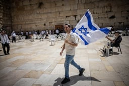 A Jewish man walking with an Israeli flag at the the Western Wall, in Jerusalem's Old City, on the morning of Jerusalem Day. May 26, 2025. 