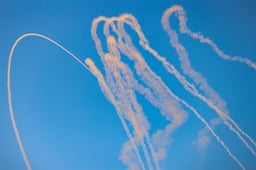 Smoke trails are seen as missiles launched from Lebanon into Northern Israel are intercepted by Israeli anti missile system