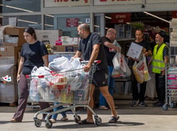 People walking with their shopping, outside a supermarket in Lod, central Israel, June 13, 2025. 