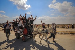 Displaced Palestinians carry food parcels and supplies from a GHF aid distribution point at the “Netzarim corridor” in the central Gaza, August 4, 2025.