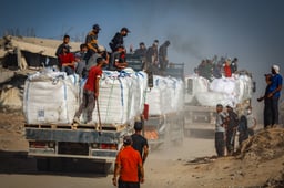 Armed Palestinians sit on trucks carrying humanitarian aid near the Zikim border crossing between Israel and Beit Lahia in the northern Gaza Strip, June 25, 2025.