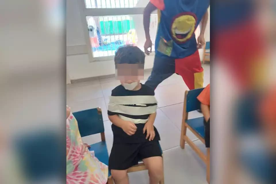The child tied to a chair with his mouth taped shut at the Kindergarten