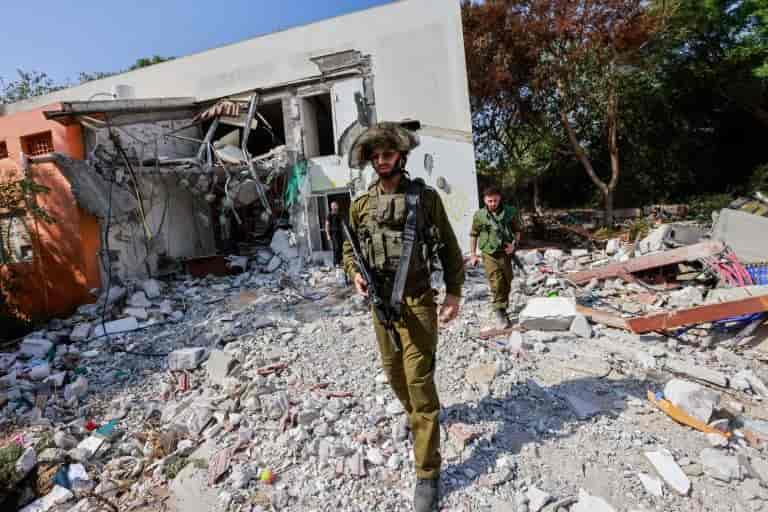 A soldier at one of the ruined houses in Kibbutz Be'eri. background