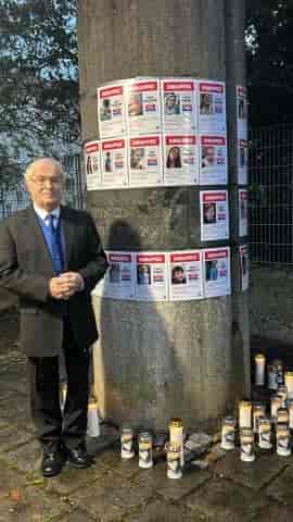 Maestro Eli Yaffe next to the pictures of the abductees background