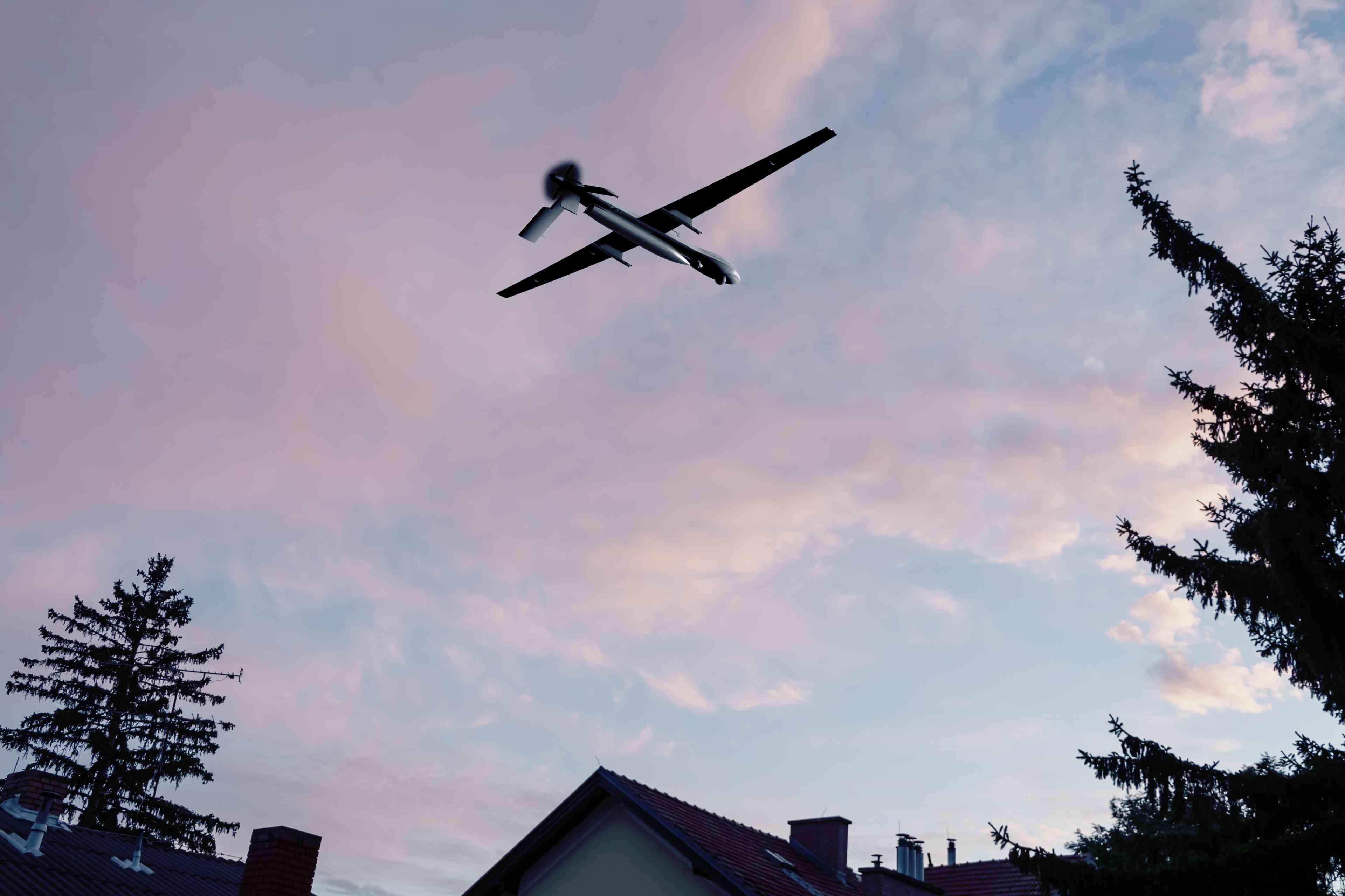 Unmanned military drone flying in the sky over residential buildings. background