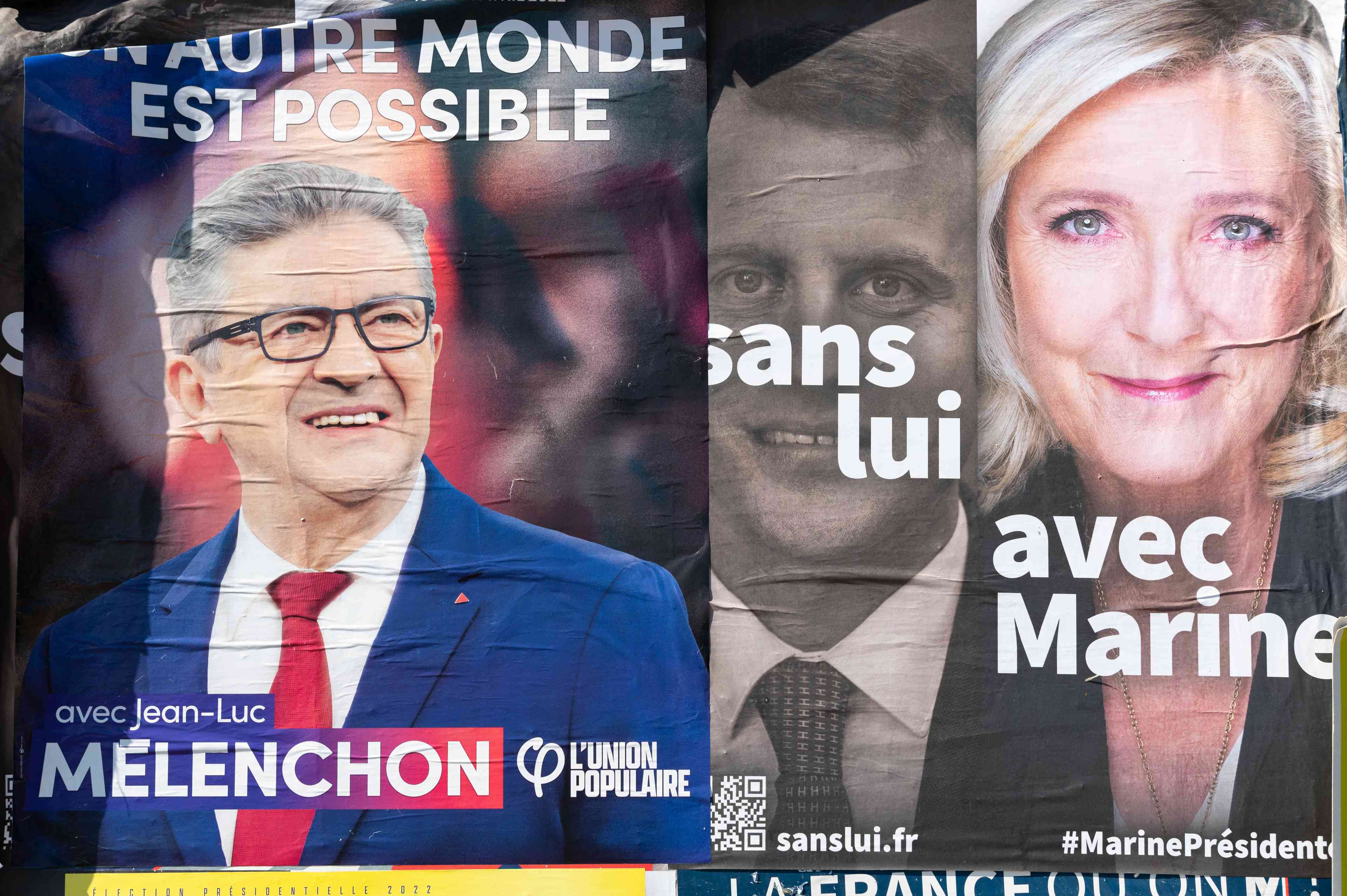 Political posters represent Macron, Le Pen and Melenchon background