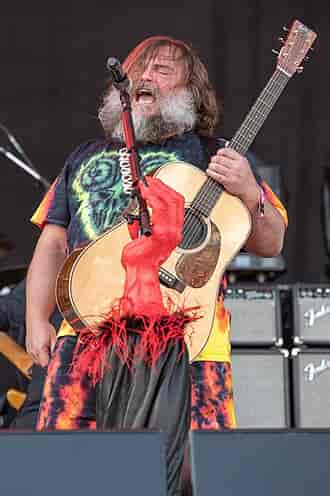 Jack Black performing with Tenacious D. background