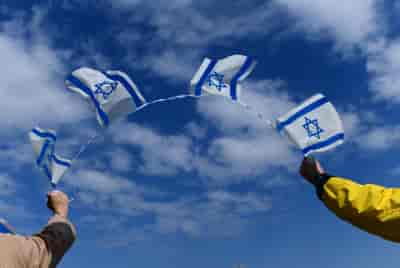 Thousands of Israelis hold signs and wave the Israeli flag on Halacha bridge in Tel Aviv background