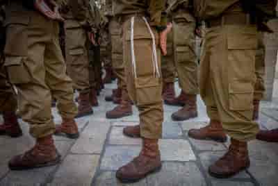 Israeli soldiers from Netzah Yehuda Battalion and family members attend a swearing-in ceremony at the Western Wall on July 10, 2024 background